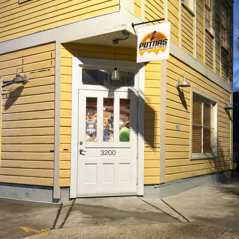 Yellow-sided Potmas Burgers & Fries restaurant entrance with white door numbered 3200 and hanging sign.